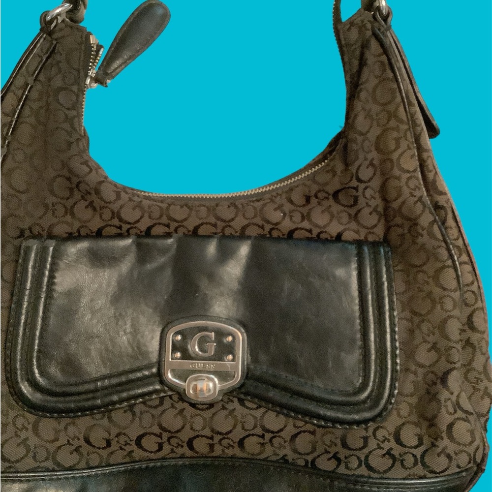 Guess Handbag, front pocket snaps shut, Inside has 1 zipper & 3 slide pockets.